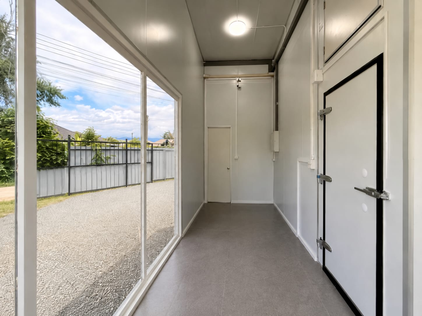 Bright office-style interior hallway with glass wall overlooking the yard