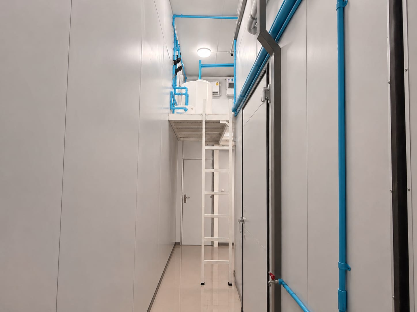 Cold room corridor with technical piping and access ladder